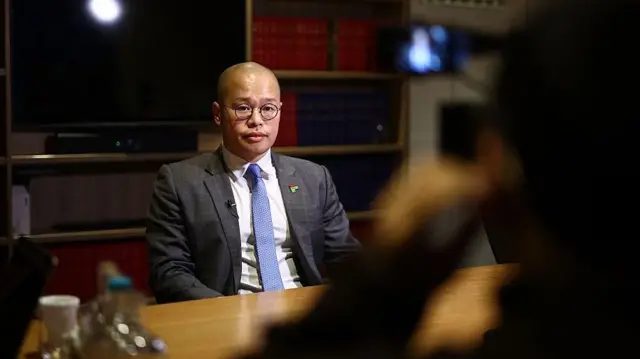 2026年2月9日，黎崇恩受访，盯着镜头。
