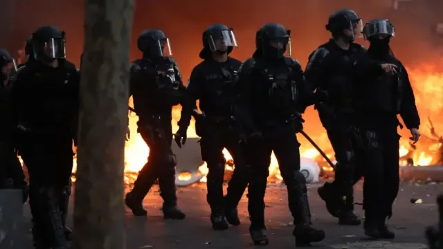 巴黎防暴警察在示威日与抗议者爆发冲突期间，走过一道燃烧中的路障（17/10/2026）