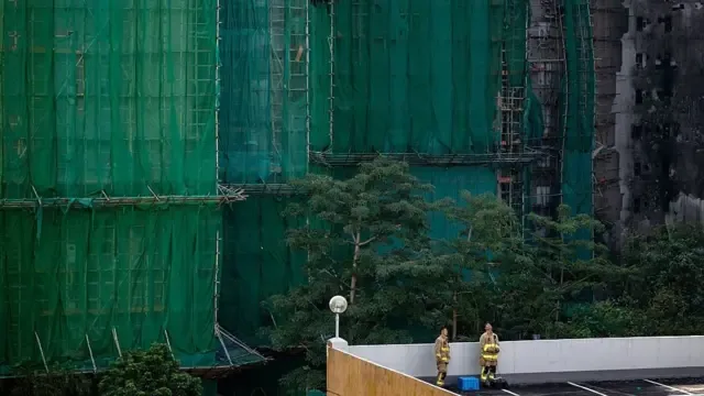 2025年11月28日，在香港大埔区宏福苑，消防员们在停车场平台上休息。