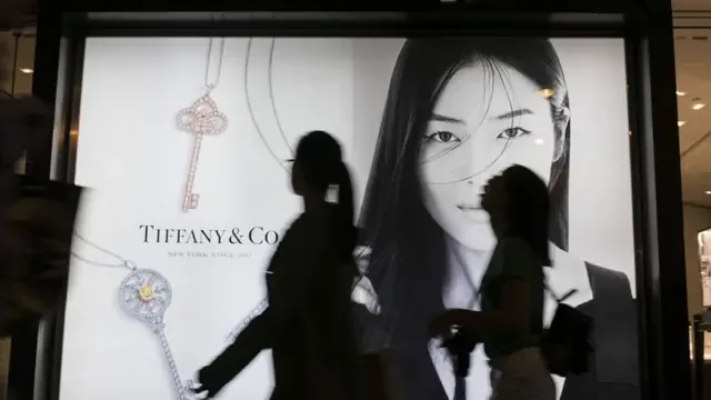 两名女子走过香港尖沙咀一处奢侈品牌广告看板。