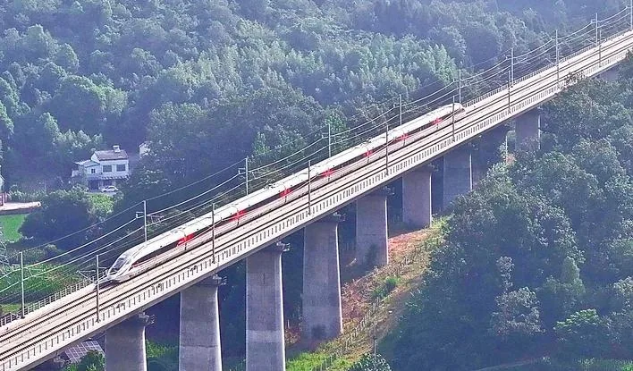 一列高速动车组在山间的高架桥上行驶