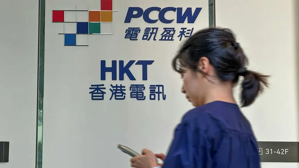 香港电讯和母公司电讯盈科的招牌，一名行人从前面走过