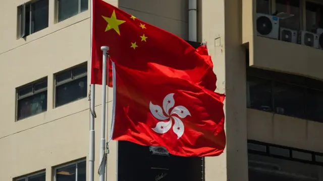一栋楼宇外悬挂的中国国旗与香港特区区旗，香港旗帜位置比中国国旗为低（24/7/2026）