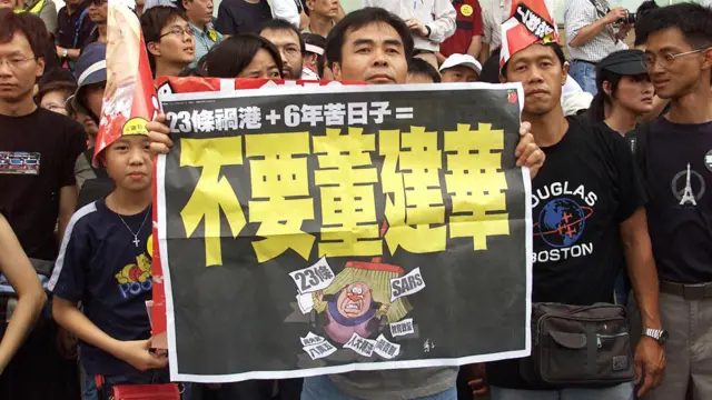 香港“七一”游行参与者举起《苹果日报》印发的“不要董建华”标语海报（1/7/2003）