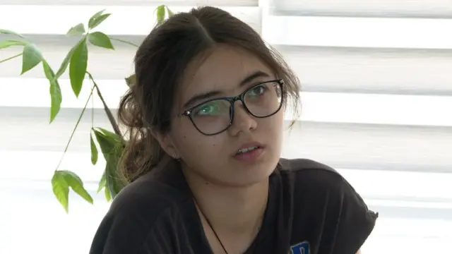 一名戴眼镜女孩的脸庞，目光望向一侧。