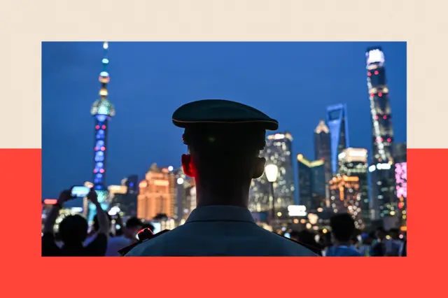 一名警察的背影，于夜晚映衬在灯火通明的城市景观前。