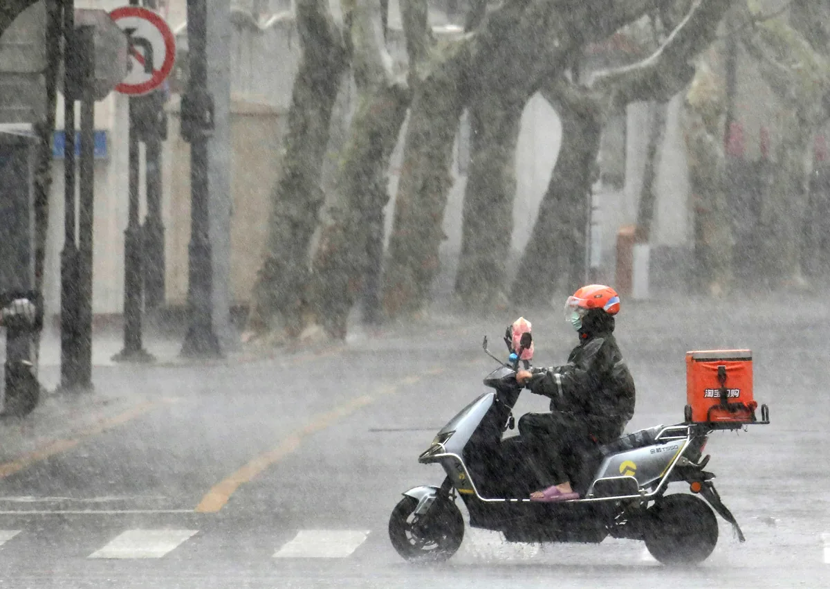 8月10日，外賣騎手冒雨在江蘇蘇州街頭行進。（新華社）