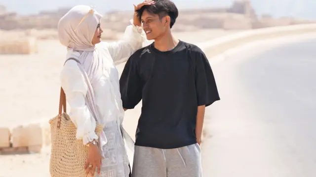 他们联手追查校长性侵指控,也在追寻公义的路上成为夫妻 4 齐亚肩上背着草编袋,穿白色上衣、戴粉红色头巾,一只手放在尤斯龙头上。尤斯龙搂着她,穿灰色运动裤和黑色T恤。