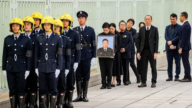 2025年12月19日，在香港“浩园”，消防员何伟豪的亲属手持他的遗像，出席其安葬仪式。