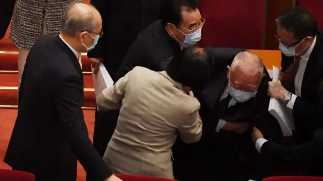 北京人民大会堂主席台上中国全国人大代表搀扶摔倒的董建华（右二）（5/3/2021）