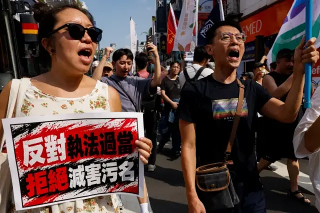 台北西门町 LGBT 群体抗议警察不当搜查同志酒吧现场，示威者举起（左）“台北真的同志友善吗”与（右）“反对执法过当，拒绝灭害污名”标语牌（4/10/2026）