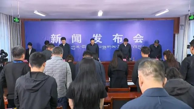 西藏吉隆镇新闻发布会现场官员与记者默哀悼念泥石流灾难死难者（中国中央电视台画面截屏30/8/2026）