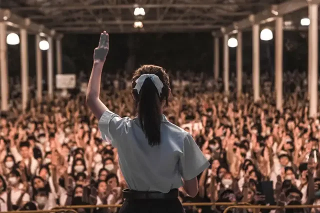 2020年8月，梅琳站在示威人群前，举起三指手势。