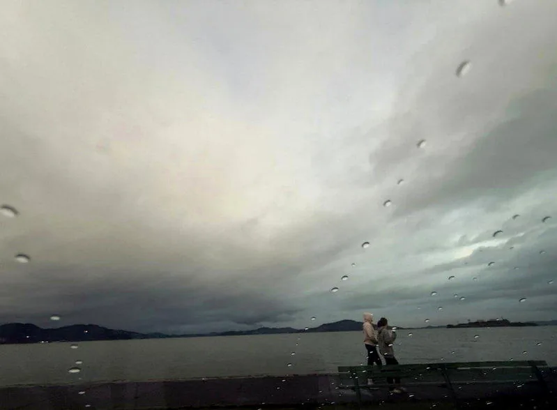 阴云下的海湾与岸边行人