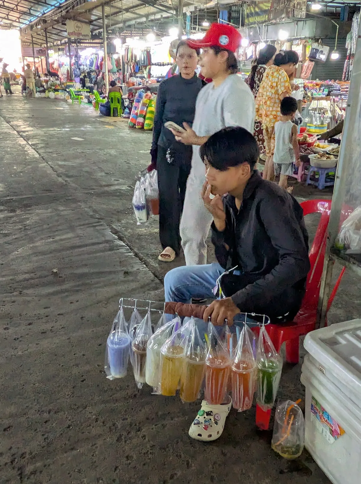市场走道中间小贩穿梭叫卖，年轻人提着饮料袋招揽客人。（黄匡宁摄）