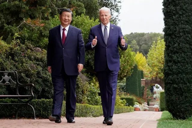 习近平（左）与拜登（右）在加州伍德赛德费罗丽庄园内散步，拜登双手比起拇指（15/11/2023）
