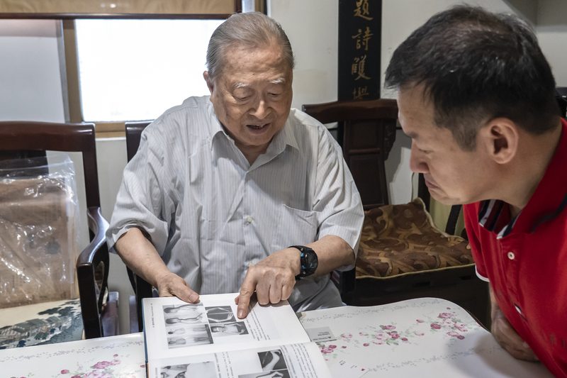 91岁吹哨医师杨子思:半世纪后重逢台湾沙利窦迈药害者 2 睽違51年,楊子思(左)翻開其著作《中國人的先天異常》,指出當年為鑑定王挺傑時拍攝的照片。(攝影/陳曉威)