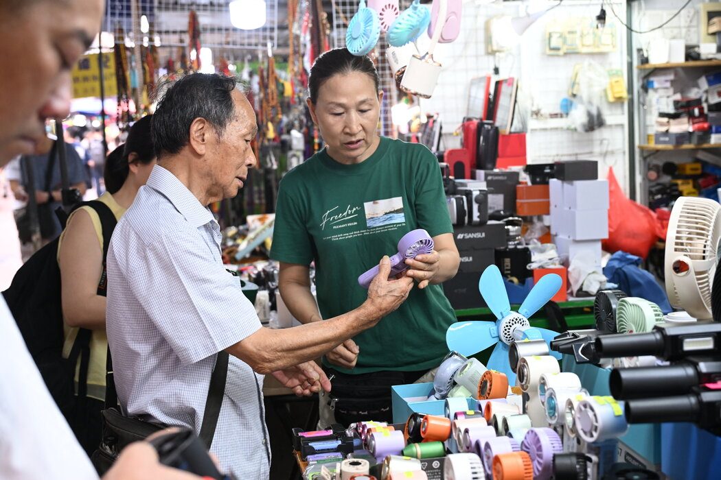 6月，人们在香港一家商店里选购便携风扇。