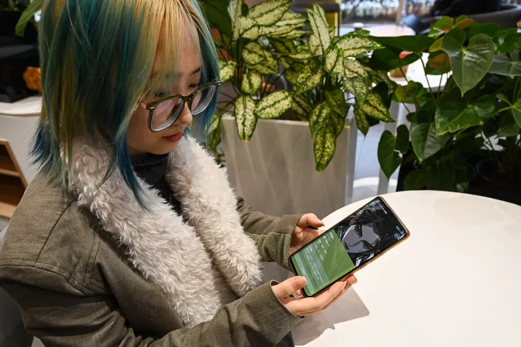 北京的一家咖啡馆里，一名用户通过中国科技公司百度开发的人工聊天机器人“万话”展示她的虚拟男友。