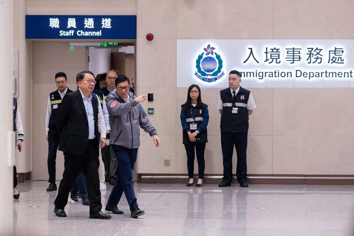 新皇崗口岸10月12日開通，政務司司長陳國基（左一）及保安局局長鄧炳強（左二）等在皇崗口岸正式啟用後與過關人士傾談。（夏家朗攝）