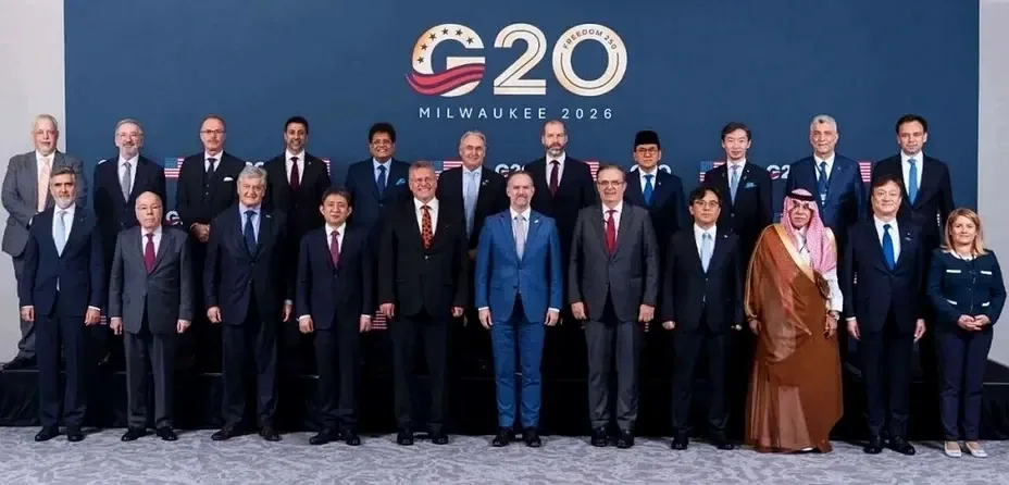 二十多人站成两排合影，背景写着“G20”和“MILWAUKEE 2026”