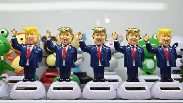 浙江义乌某展场内，五个以唐纳德·特朗普为原型、带有夸张漫画风格的人偶整齐排列在附有小型太阳能板的白色底座上。每个人偶都身穿蓝色西装、系着红色领带，并举起一只手臂。（资料图片）
