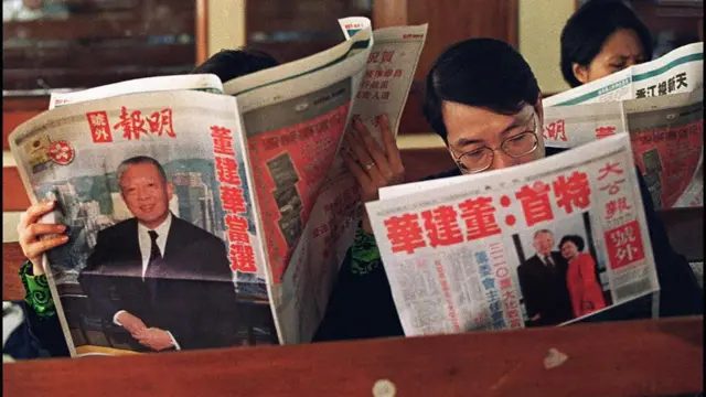香港一艘天星小轮上乘客阅读报道董建华当选首任香港特首的报纸号外（11/12/1996）