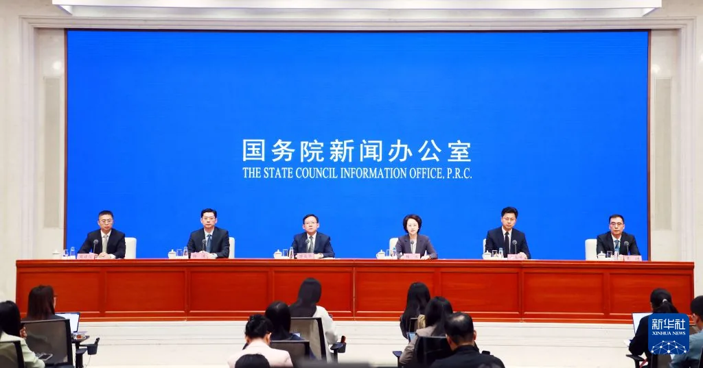 国务院新闻办公室发布会现场，发言人坐在蓝色背景前的长桌后。