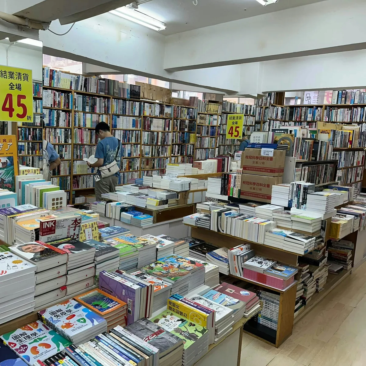 香港旺角乐文书店内,顾客在书架和清货告示旁翻阅书籍