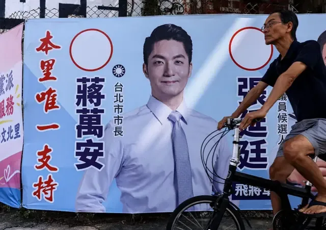 2026年10月15日，台北街头一名男子骑车经过印有国民党台北市长候选人蒋万安肖像的竞选看板。

