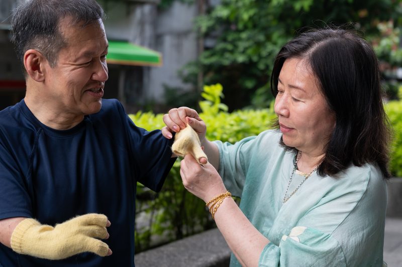 沙利窦迈药害60年 台湾3位「沙儿」的生命故事 18 三姊王麗麗(右)為王挺傑織特製手套。(攝影/謝佩穎)