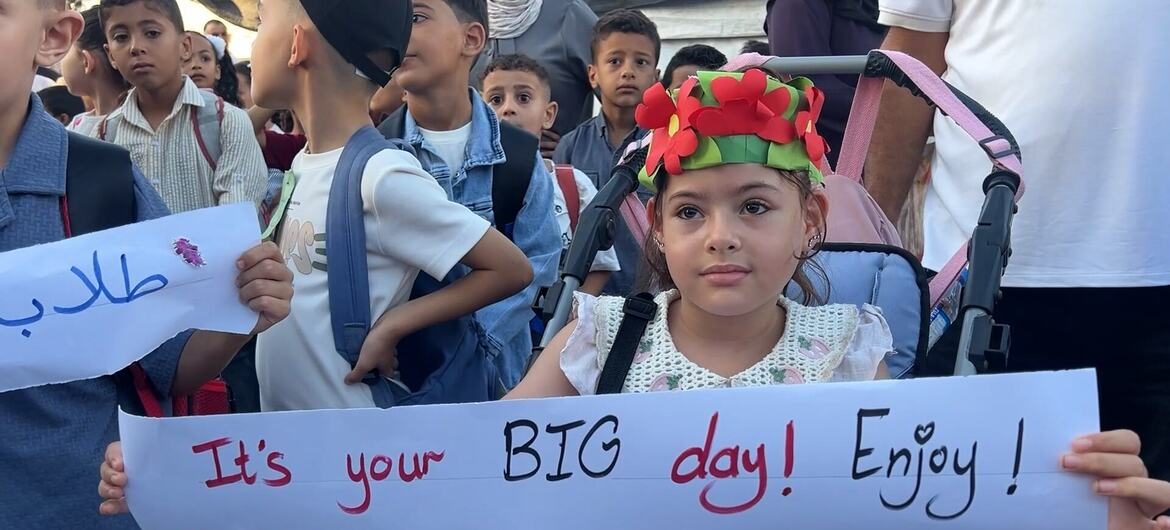 在加沙地带中部努塞拉特难民营的一所联合国近东救济工程处学校里，一名坐在轮椅上、头戴花冠的小女孩与其他孩子一起举着一块牌子，上面写着“这是你的大日子！好好享受吧！”。