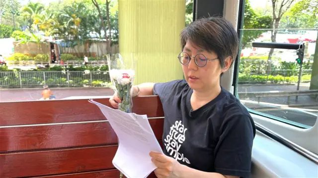 刘家仪坐在电车内，手持一束花及文件。