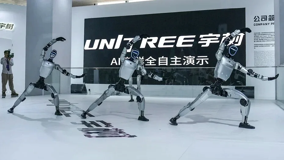 三台人形机器人在写有“UNITREE 宇树”字样的展台前摆出同样的动作