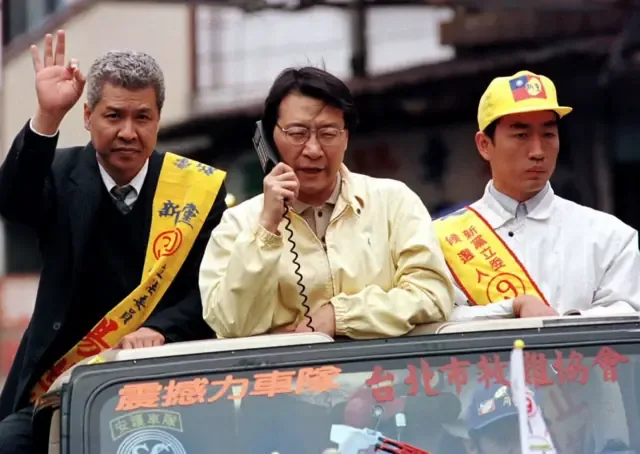 反对党新党主席赵少康于11月28日在台北竞选期间暂时停下脚步，以行动电话交谈；一旁的同僚则向道路两旁的支持者挥手致意。即将于周六举行的选举，被视为执政的国民党自1945年在台湾掌权以来面临的最严峻考验。