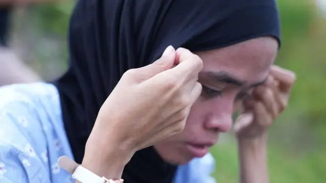 他们联手追查校长性侵指控,也在追寻公义的路上成为夫妻 2 苏克玛弯着身整理黑色头巾,看起来神情痛苦。她穿着一件有白色小花图案的蓝色上衣。