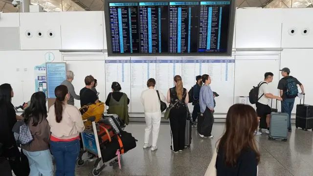 2026年4月1日，人们在香港国际机场查看航班资讯显示器。