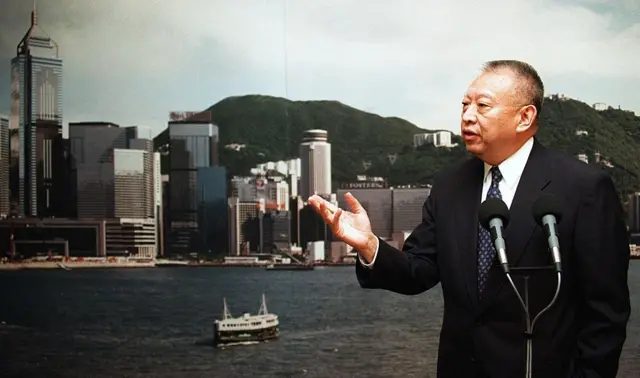 背靠香港海景，董建华对着麦克风讲话