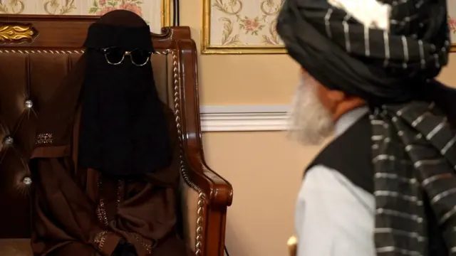 离婚、智能手机与管控——BBC观察塔利班如何治理阿富汗 1 一名身穿棕色长罩袍的女子坐在一张铺有软垫的木制长椅上,正与省长交谈。她的头部和脸部被黑色头巾遮盖,并佩戴太阳眼镜,因此看不见她的眼睛。
