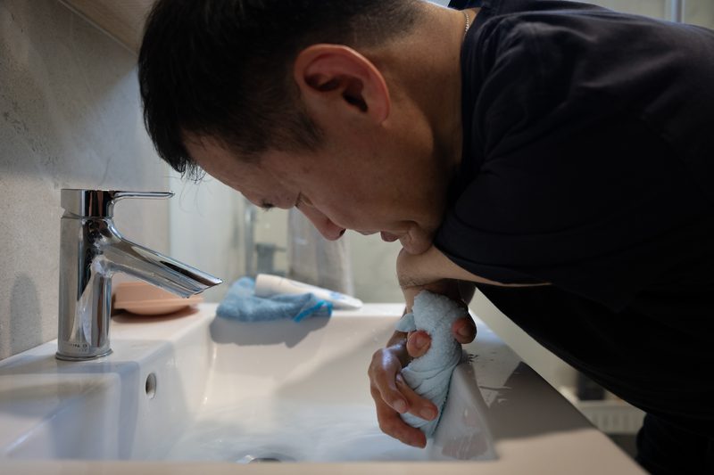 沙利窦迈药害60年 台湾3位「沙儿」的生命故事 21 擰毛巾是高難度挑戰,王挺傑得將下巴壓住比較無力的左手握住毛巾一頭,較長的右手抵住洗手台擰另一頭,一起施力,才能擰乾。(攝影/謝佩穎)