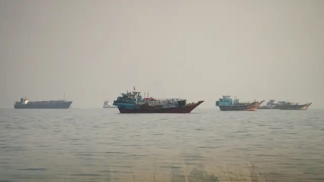 在阴沉的天空下，多艘船只航行于霍尔木兹海峡。