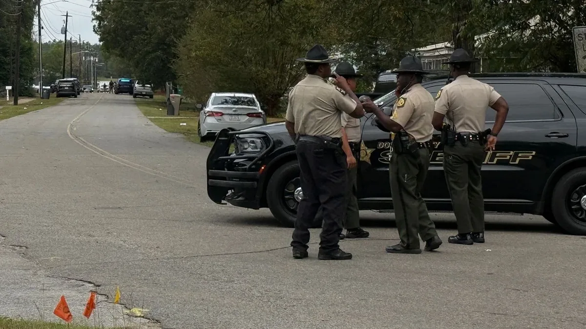 多利县警长办公室的几名警员站在一辆警车旁